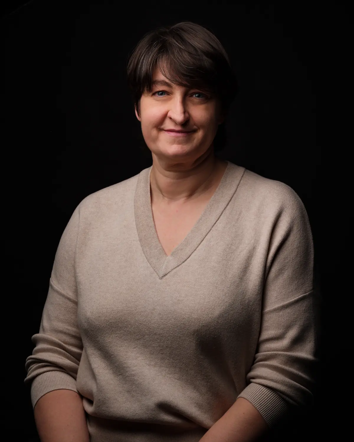 Portrait d'une collaboratrice en pull beige, fond sombre — BLH Photographie