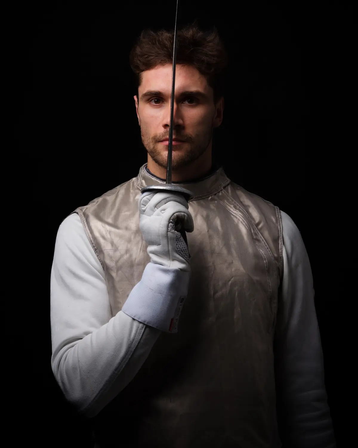 Portrait d'un escrimeur, épée devant le visage, éclairage dramatique — BLH Photographie